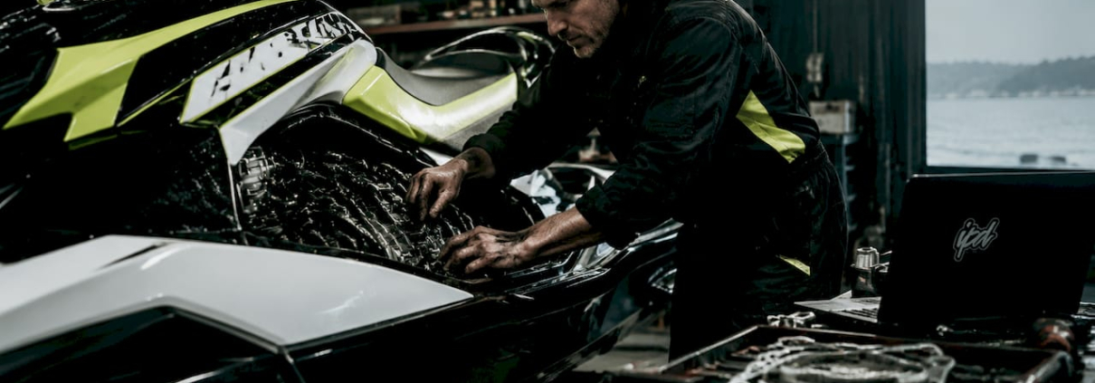 Technician tuning jet ski engine in workshop