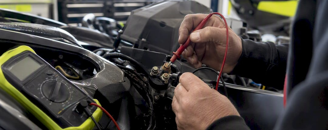 Hands testing PWC starter solenoid with multimeter